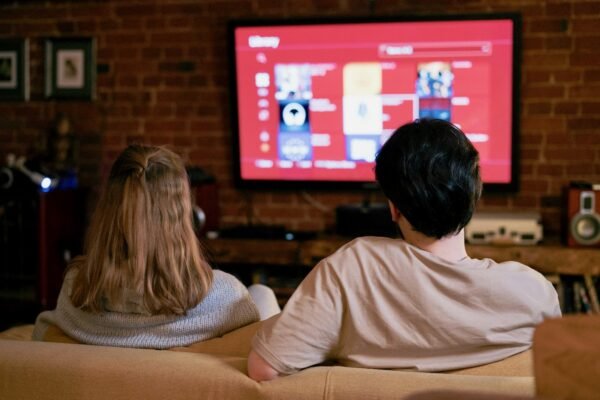 young man and woman watching smart TV on brick wall