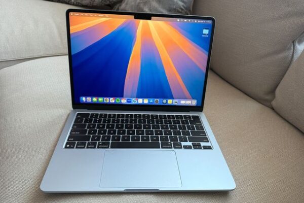 Front view of an open Apple MacBook Air 13-inch 2025  laptop sitting on a couch with the screen showing the desktop